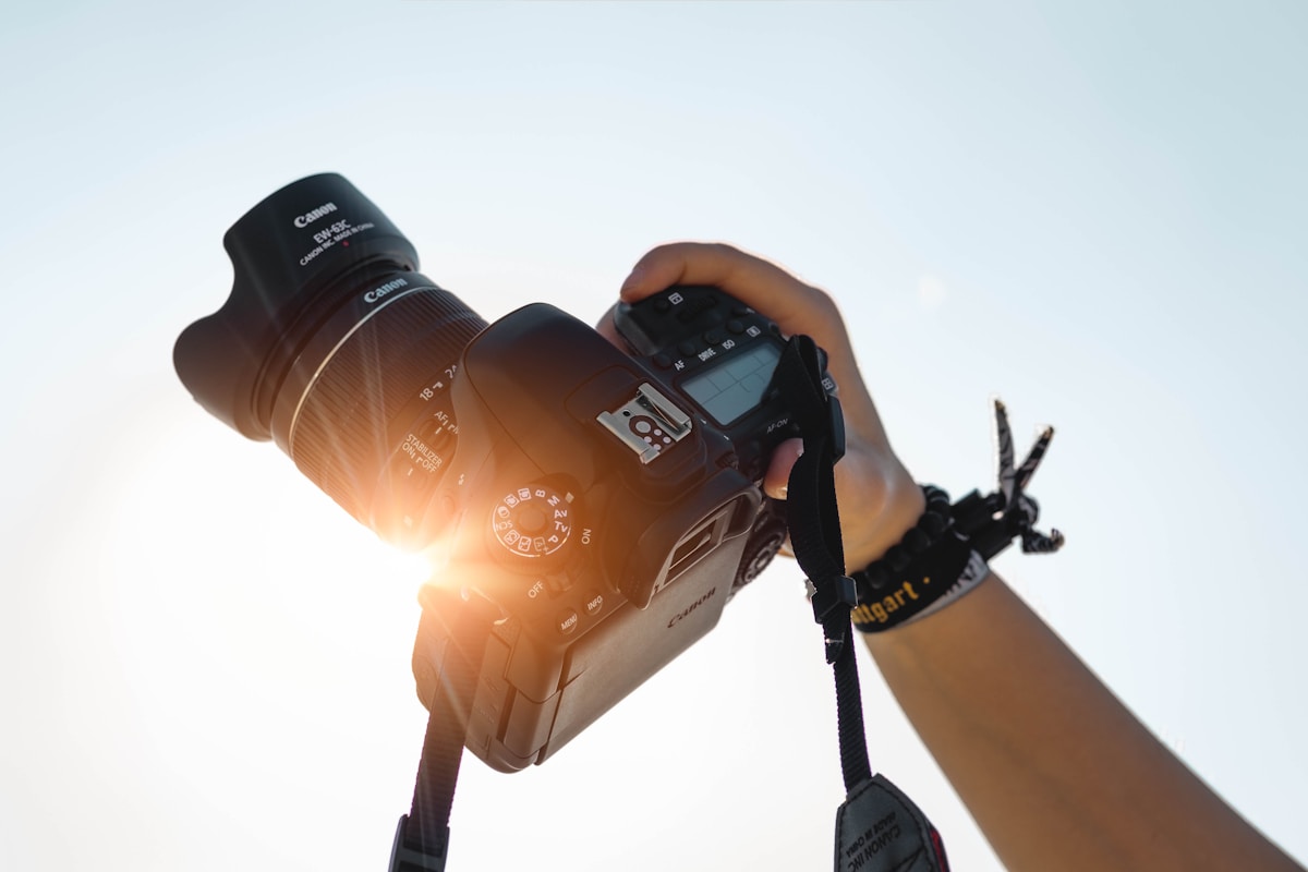 Person holding a professional camera taking photos for freelance photography side hustle