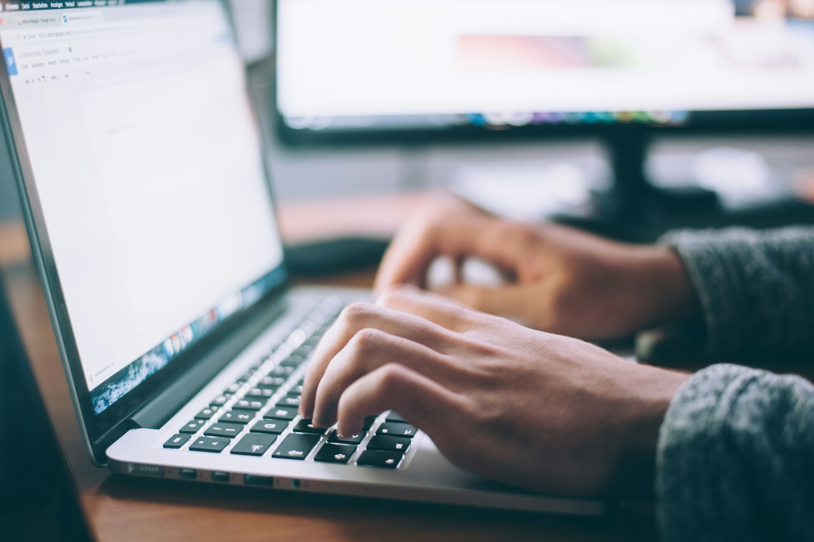 Person working on freelance writing at laptop in coffee shop with warm lighting